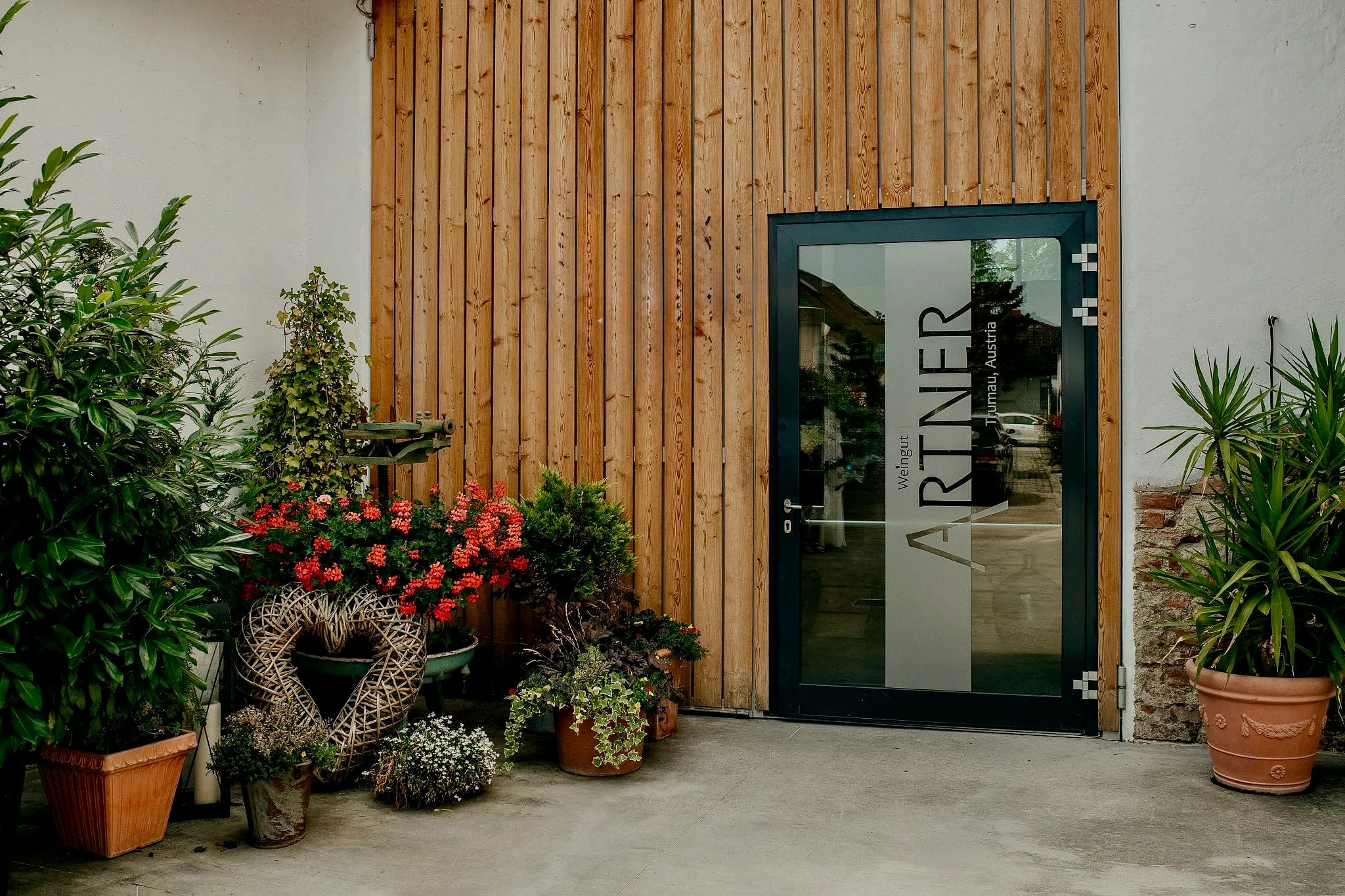 Entrance to Weingut Artner, with the name engraved on the glass door and potted plants framing the wood-paneled wall
