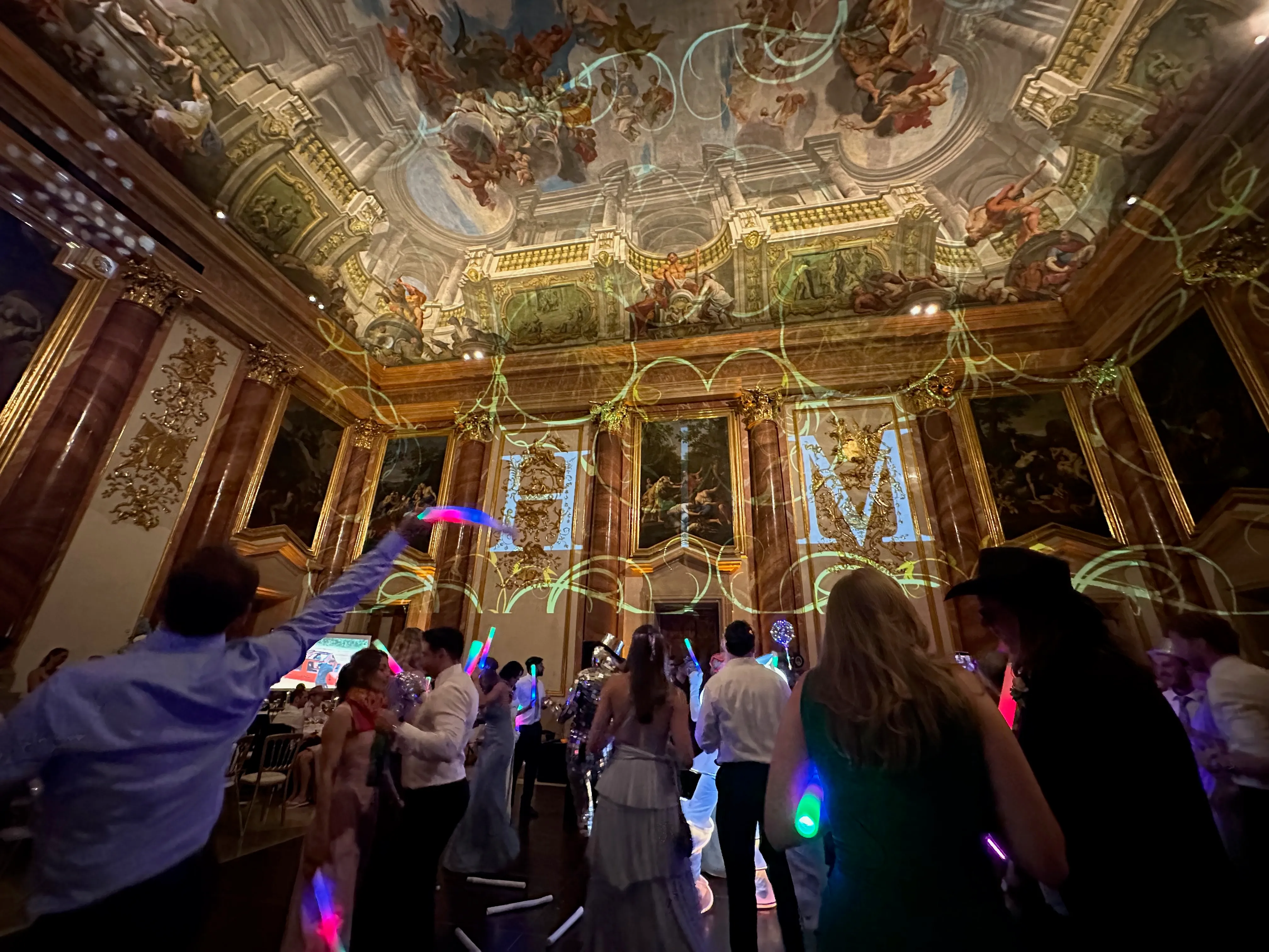 Wedding reception under the frescoed ceiling, with the couple's initials projected on the wall