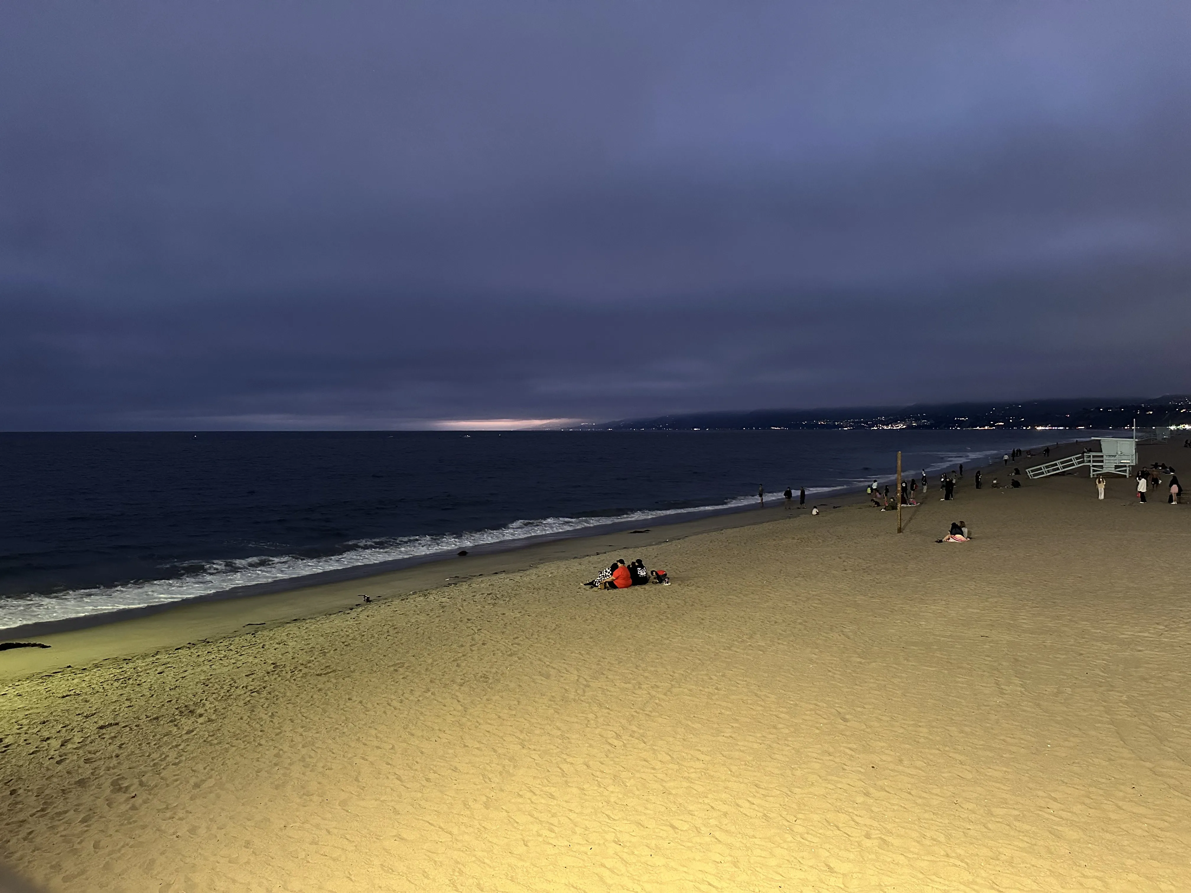 Santa Monica beach at dusk with the pier glowing in the distance